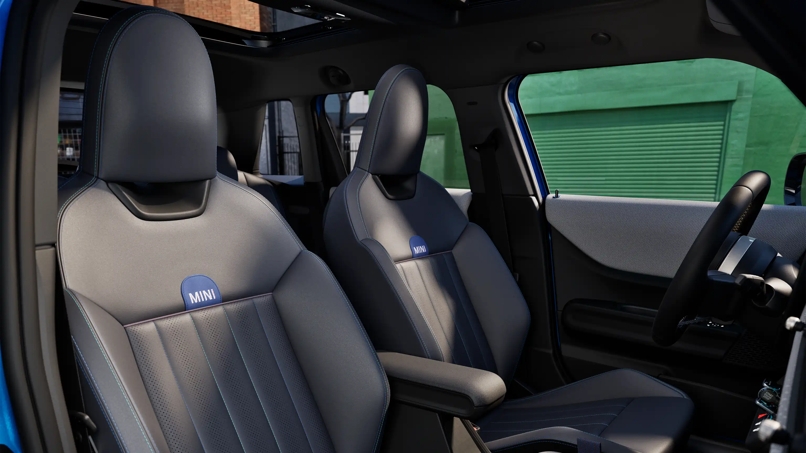 Interior perspective of the MINI Cooper 5-Door is showing the dashboard, steering wheel, round display, panorama glassroof  and back of the frontseats.