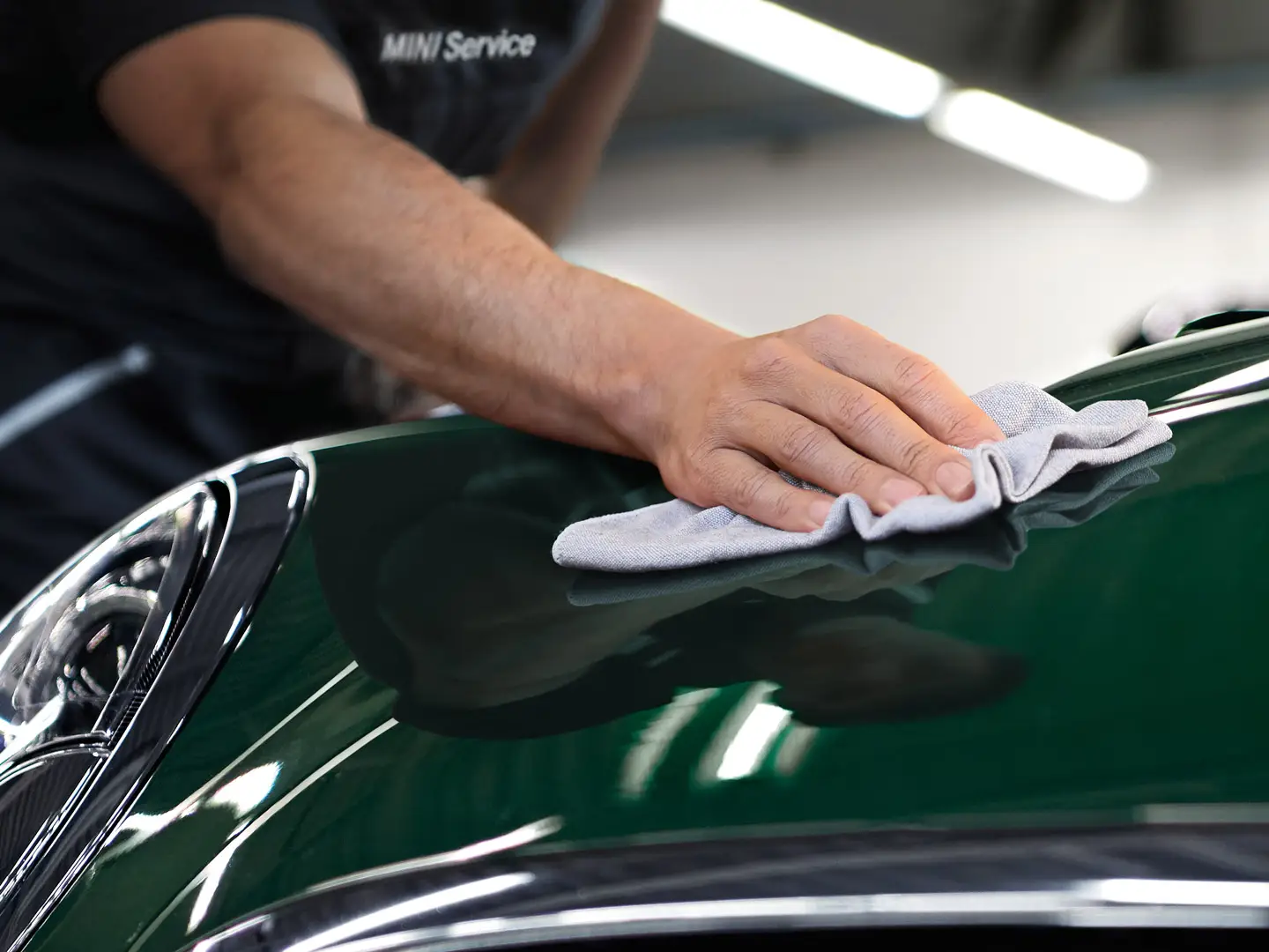MINI Cleaning and Care – technician polishing MINI Racing Green surface.
