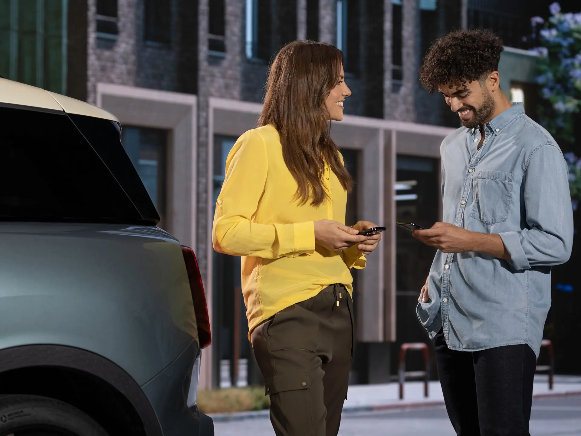Man and a woman standing next to a MINI, contacting a MINI service parter using their phones