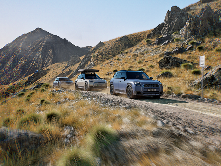 Image of multiple MINI Countryman Untamed Edition models driving offroad on a mountain road.